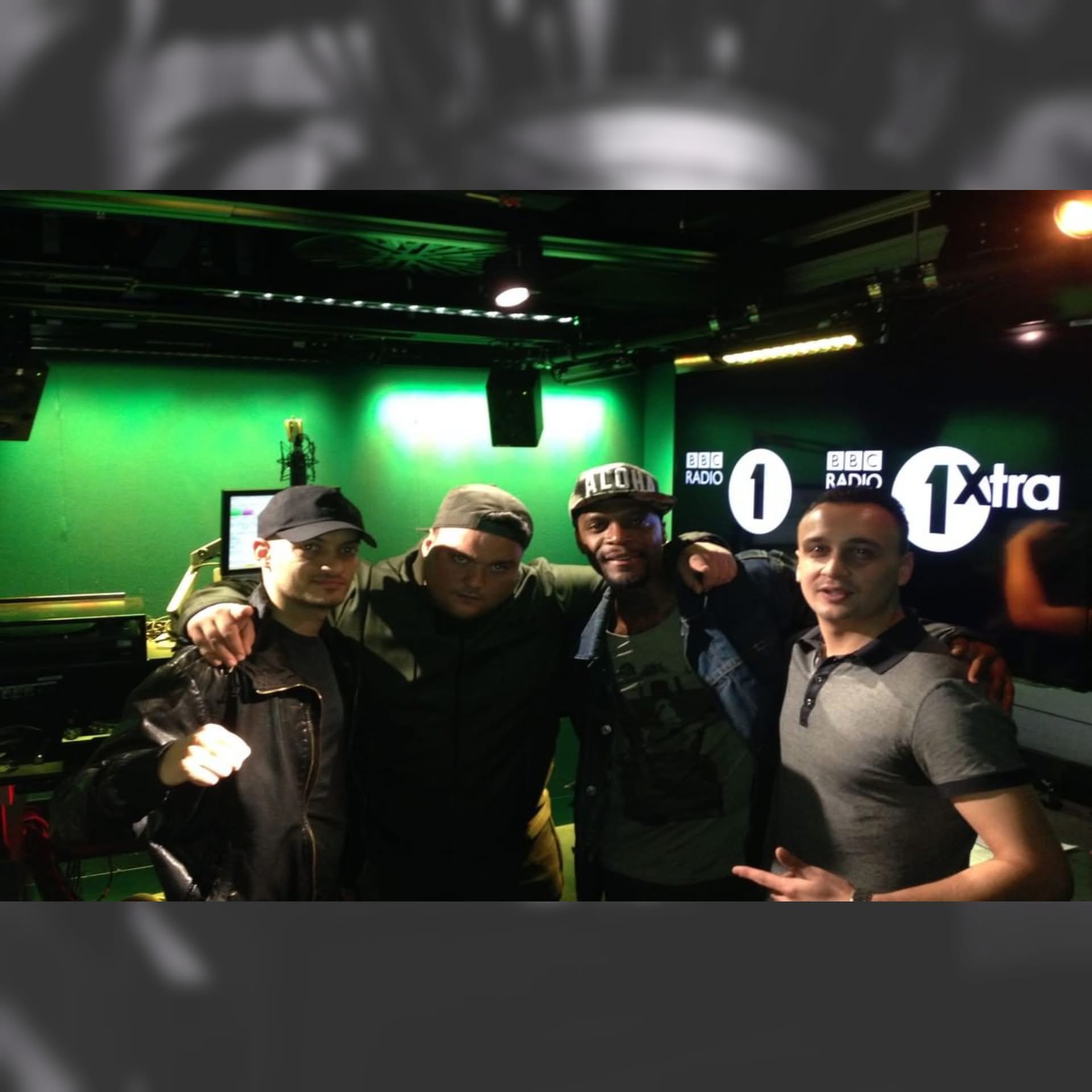 Michael Darius Eastwood with three artists inside the BBC Radio 1 and 1Xtra studio, the station logos on the wall behind