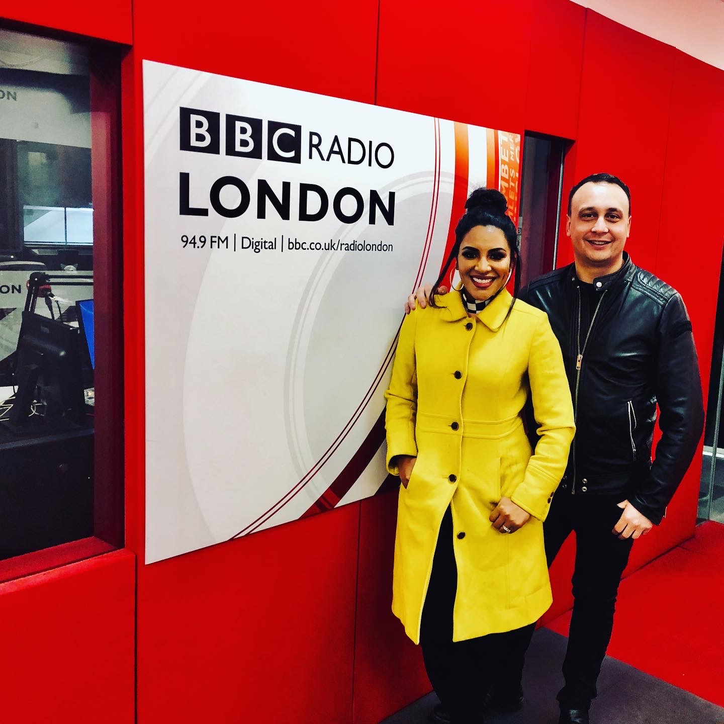 Michael Darius Eastwood with the artist Crystal Starr beside the BBC Radio London studio sign, the later white and red branding, an on-air studio visible through the glass