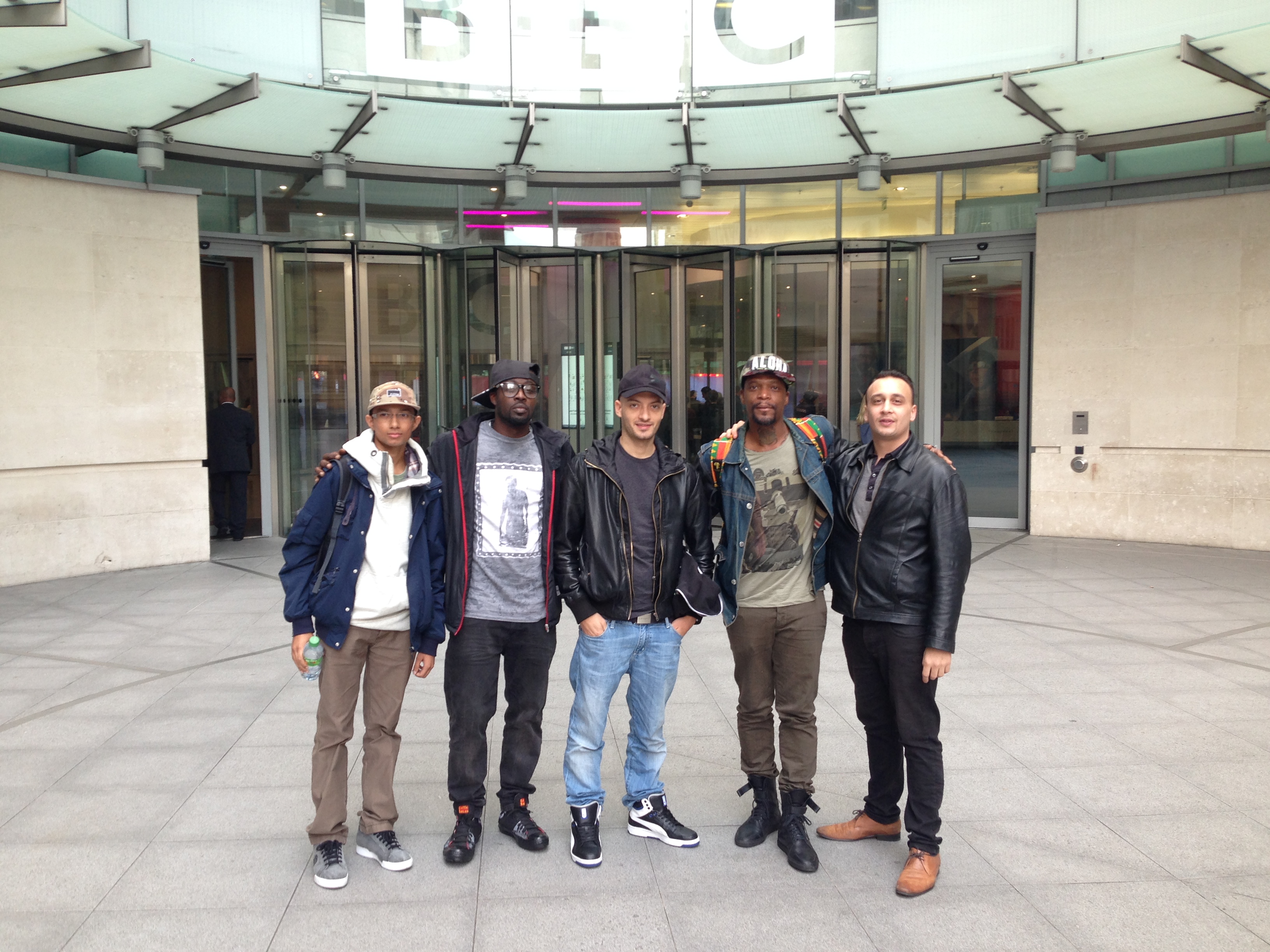 Michael Darius Eastwood standing with the hip-hop group Dead Prez and colleagues outside the main entrance of BBC Broadcasting House in London