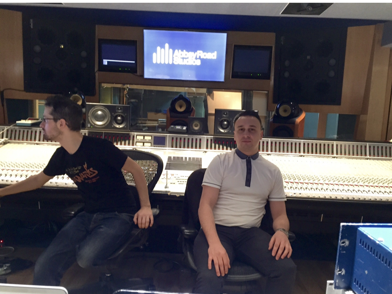 Michael Darius Eastwood seated at the mixing console in an Abbey Road Studios control room, the studio logo on the screen behind, an engineer working alongside