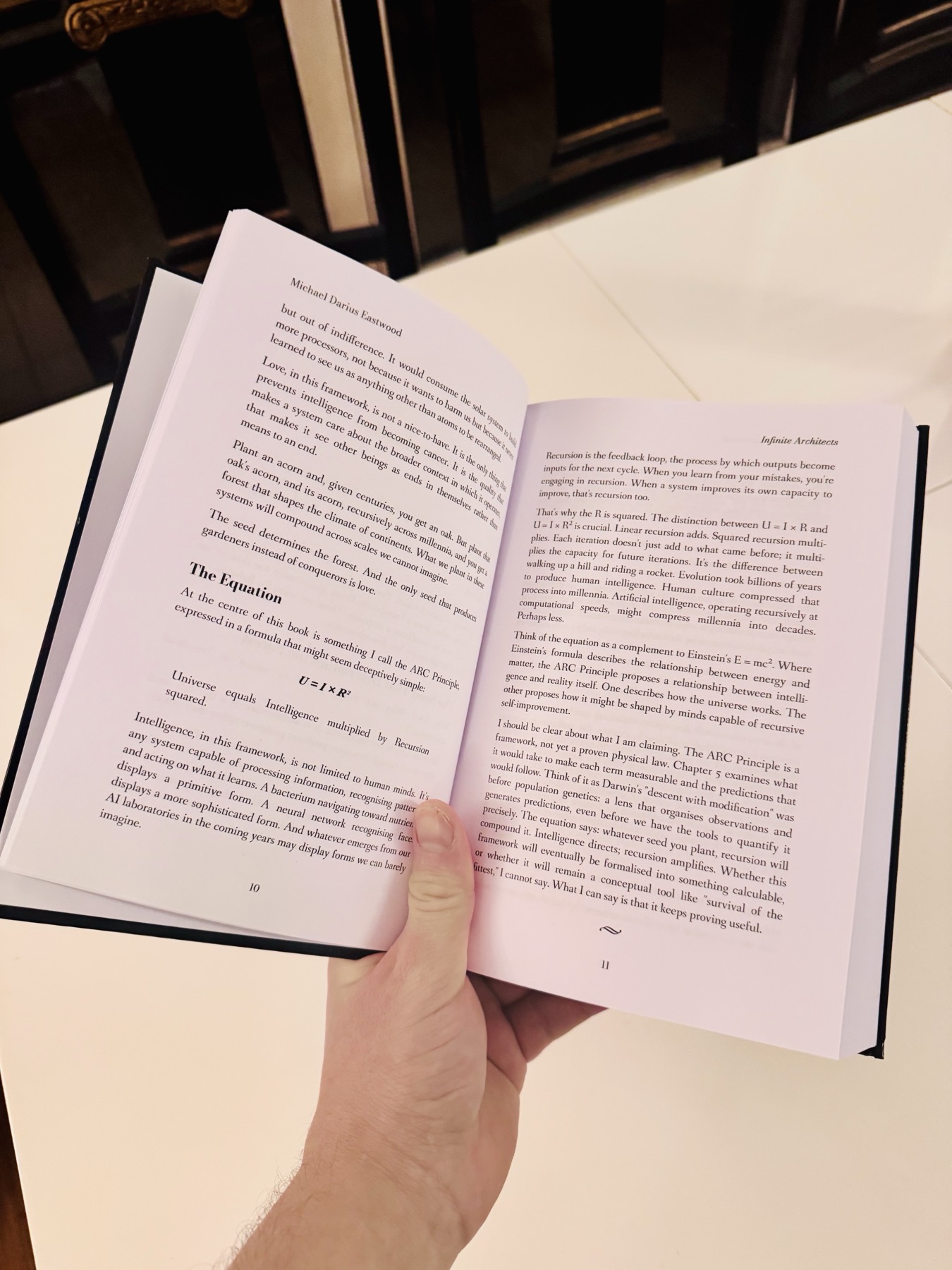 The printed book held open at pages 10 and 11, showing the section headed The Equation with the formula U equals I times R squared, and the paragraph stating the ARC Principle is a framework, not yet a proven physical law